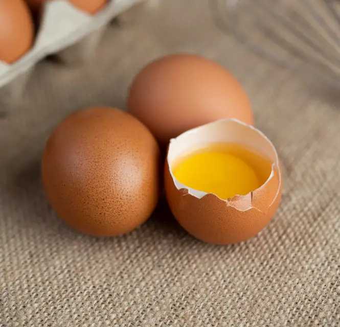 3 huevos, uno abierto con la yema a la vista.